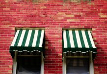 Welk zonnescherm kies jij: een terrasscherm of uitvalscherm? Twee zonneschermen op bakstenen muur
