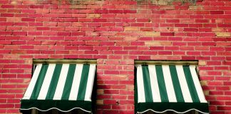 Welk zonnescherm kies jij: een terrasscherm of uitvalscherm? Twee zonneschermen op bakstenen muur