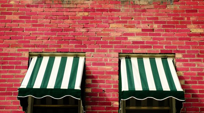 Welk zonnescherm kies jij: een terrasscherm of uitvalscherm? Twee zonneschermen op bakstenen muur